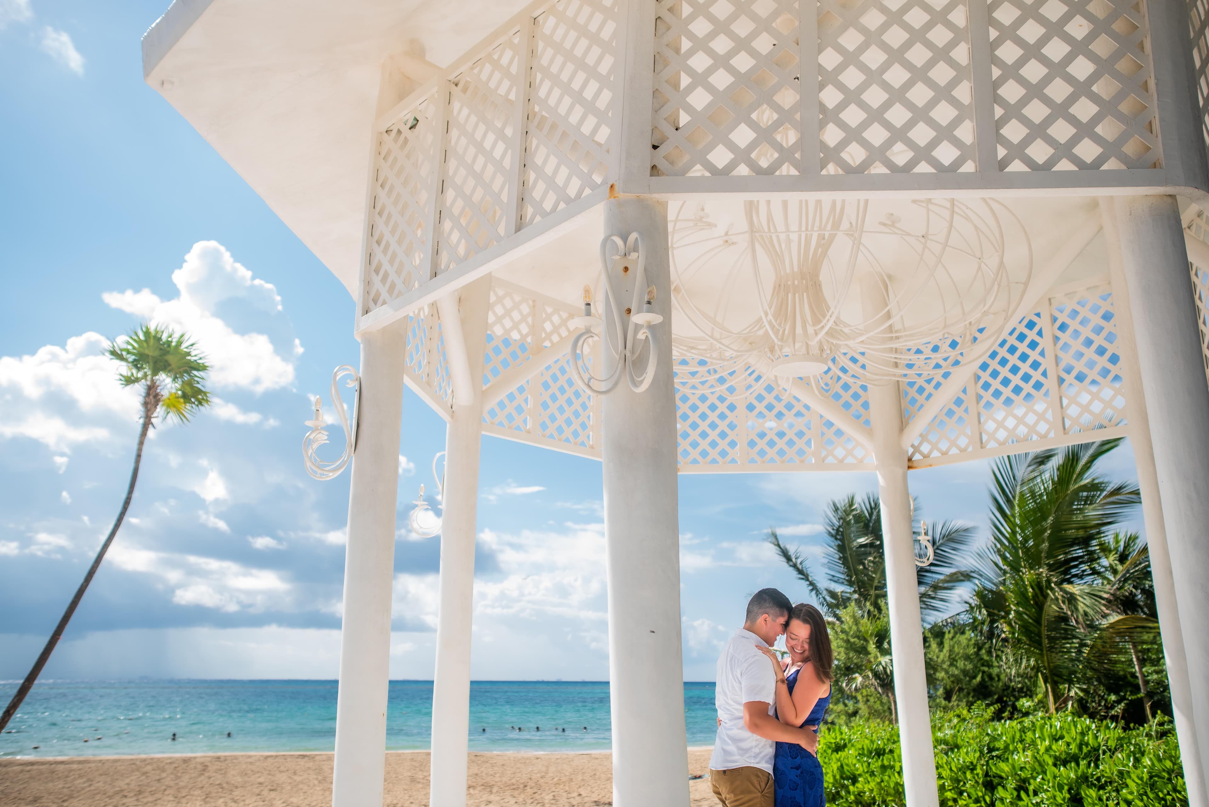 Eli and Hannah holding each other in a white gazebo from a distance.